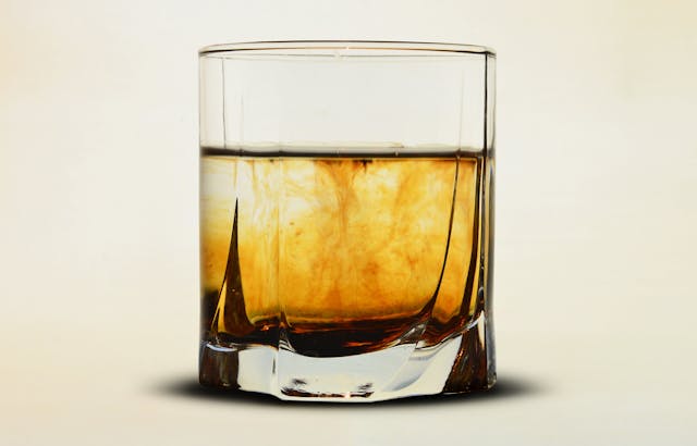 A clear glass filled with bourbon.