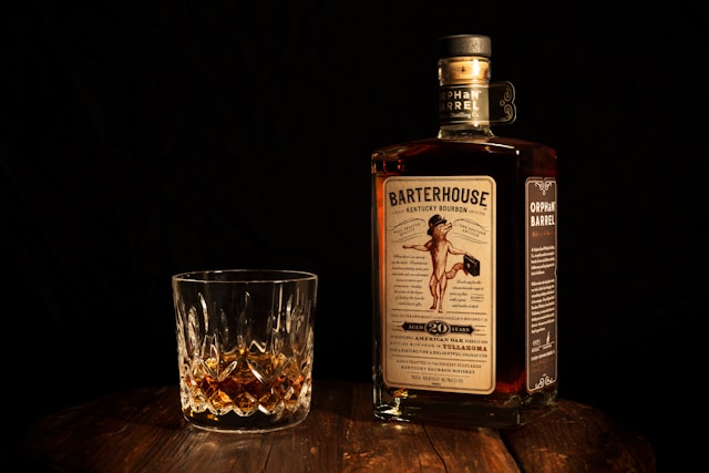 A bottle of Orphan Barrel Barterhouse bourbon and a glass beside it.