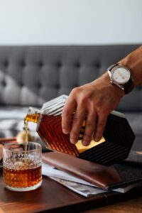 A person pouring whiskey on a crystal glass.