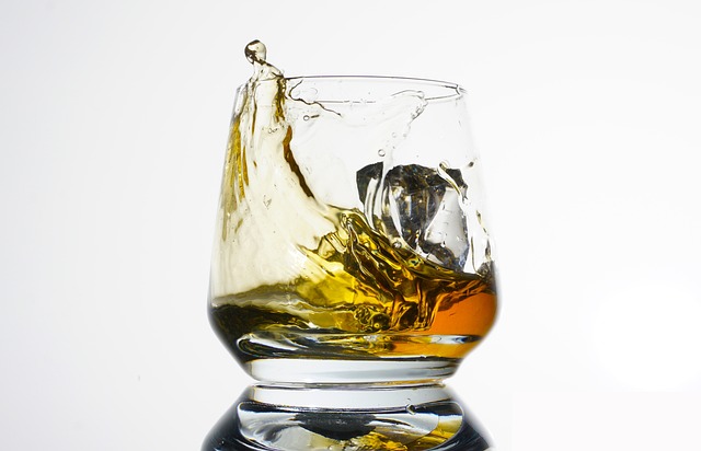 A close-up of a glass of whisky with ice, capturing the dynamic motion of the liquid splashing within the glass.