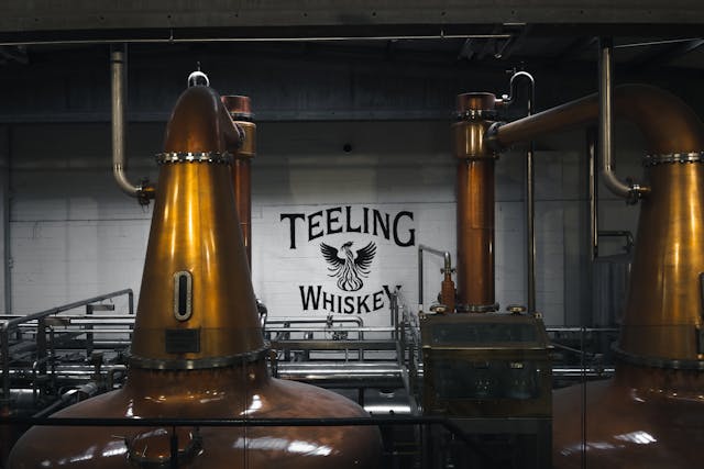 The interior of the Teeling distillery, featuring copper pot stills and the "Teeling Whiskey" logo on the wall.