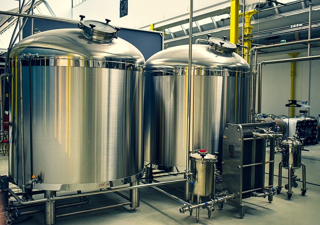 Two large, shiny stainless steel fermentation tanks in a distillery.