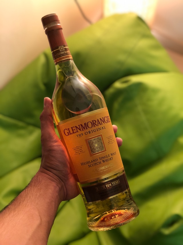 A hand holding a bottle of Glenmorangie Original 10-year-old Highland Single Malt Scotch Whisky.