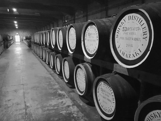 A black-and-white photo of whisky barrels in a distillery warehouse.