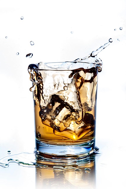 A glass of whiskey with ice cubes splashing, showcasing a refreshing and dynamic moment with vibrant clarity.