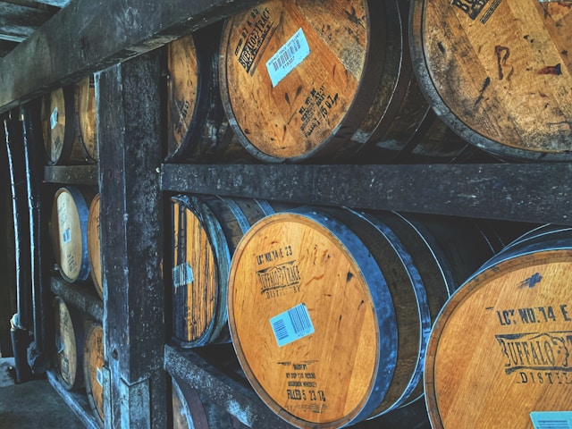 Stacked wooden whiskey barrels aging in a distillery, showcasing the traditional craft of whiskey production.