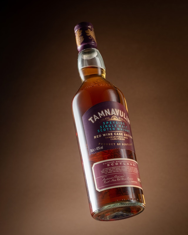 Tamnavulin Speyside single malt Scotch whisky bottle, Red Wine Cask Edition, displayed against a warm gradient background.