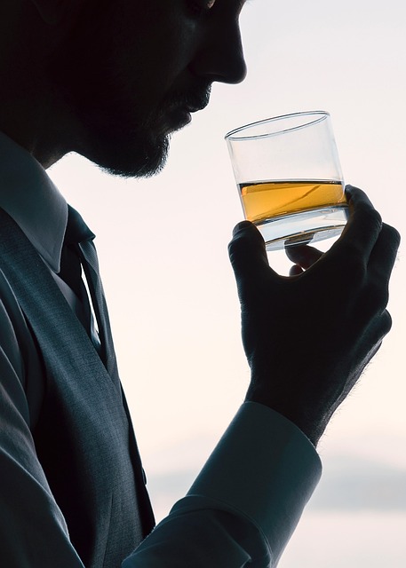 A man in a suit savoring a glass of whiskey, highlighting the art of whiskey tasting and appreciation.