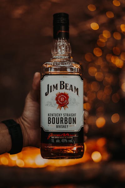 A hand holding a bottle of Jim Beam Kentucky Straight Bourbon Whiskey.